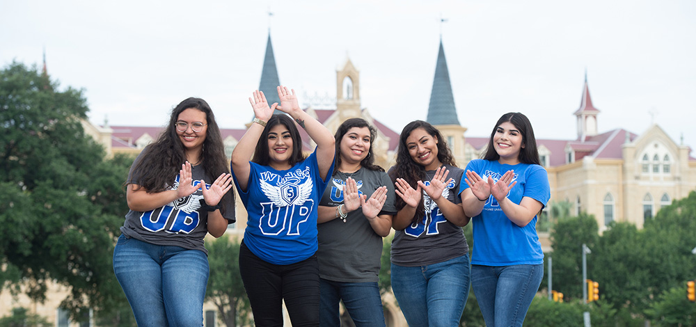 Group of students showing wings up hand symbol