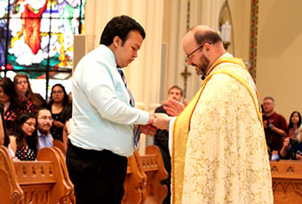 Male student receiving ring blessing in chapel
