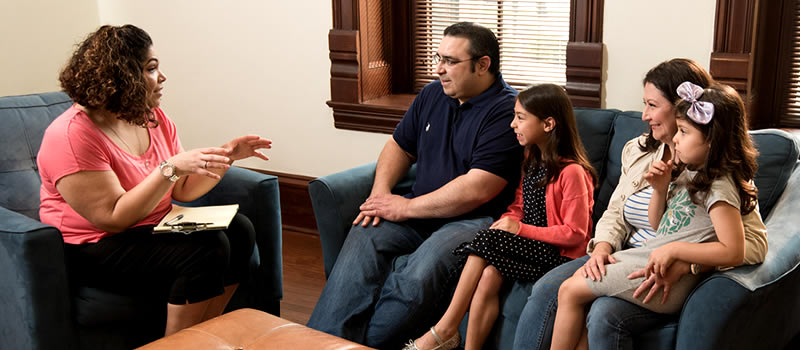 Family sitting on couch during session with social worker