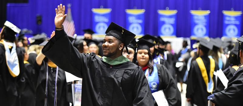 Male graduate smiling waving hello