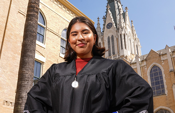 Student in regalia with steeple in background