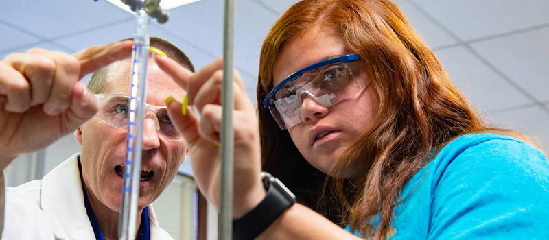 Chemistry professor and student observing vial