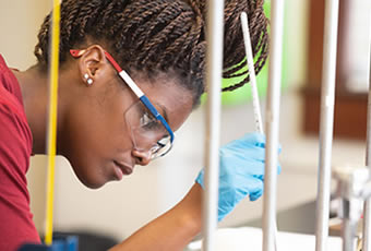 Female student wearing goggles conducting labs