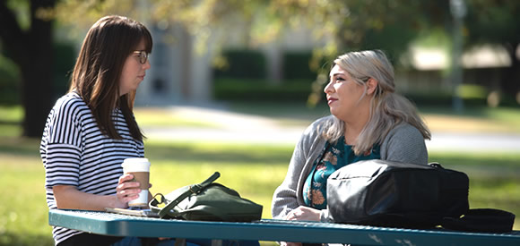 Female students talking at table outside