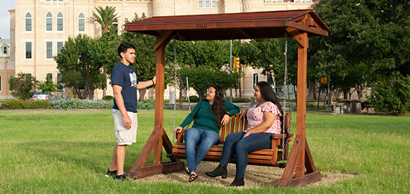 Students talking outside on a swing