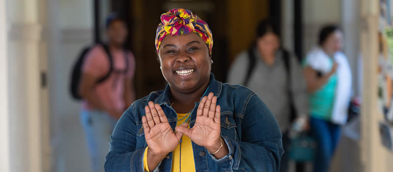 Female staning in hallway showing wings up hand symbol