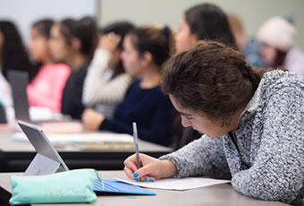 Female-student-sitting-writing-on-paper