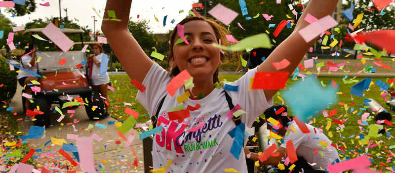 female with hands in the air with confetti