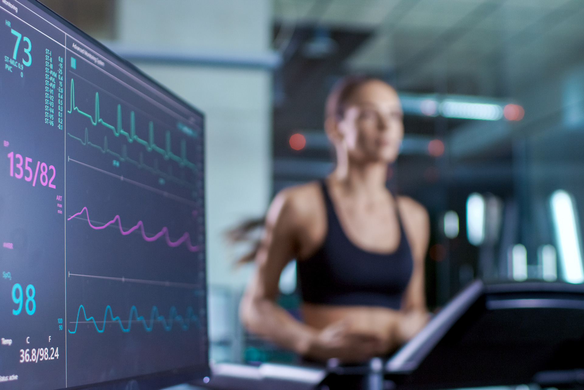 Sports science lab with athlete on treadmill and heart monitor, showing kinesiology students using sports analytics to study performance and health.