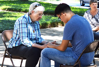 Sister and male student holding handing praying