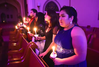 Row of students in chapel holding lite candles