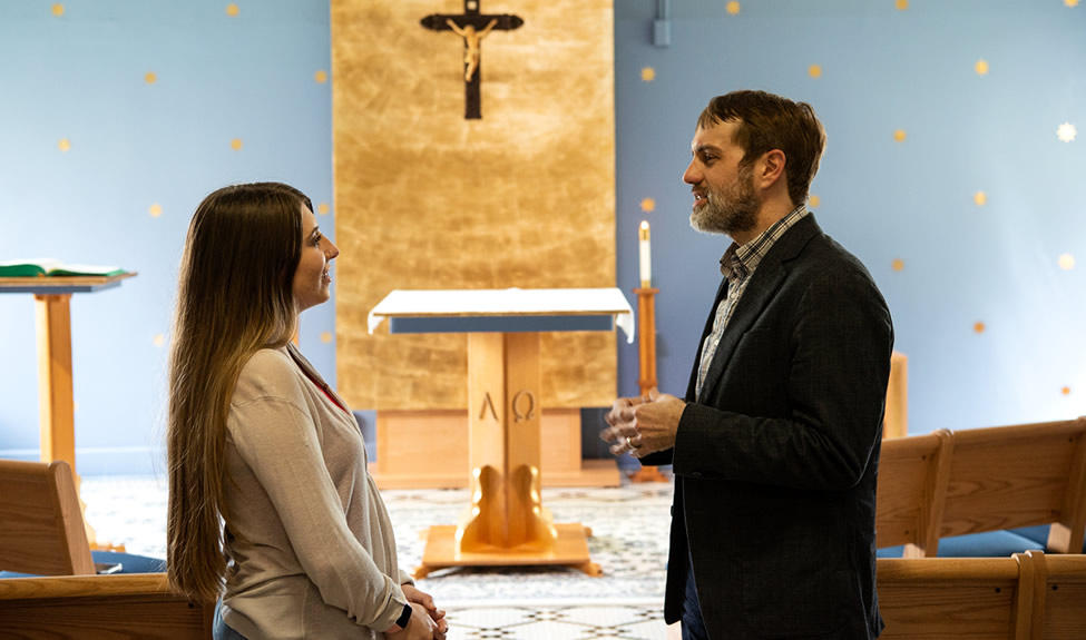 Staff and student standing talking in chapel