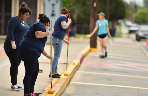 Female voluteers painting parking curb