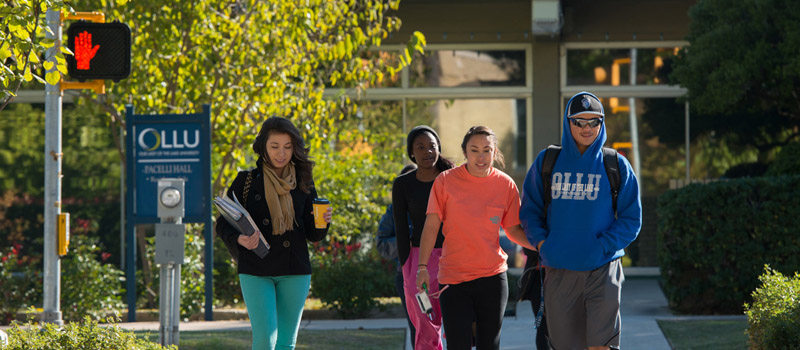 Group of students walking across the street from one side of campus to another