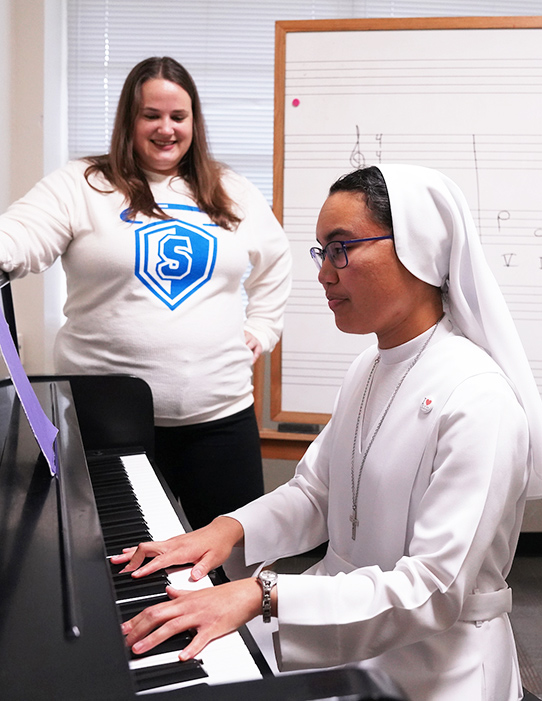 Professor Hajek observing student playing piano