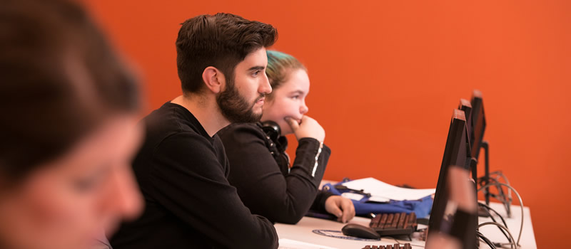 Two students sit at computers in classroom