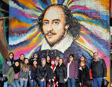 Group of students on international tour standing in front of wall art