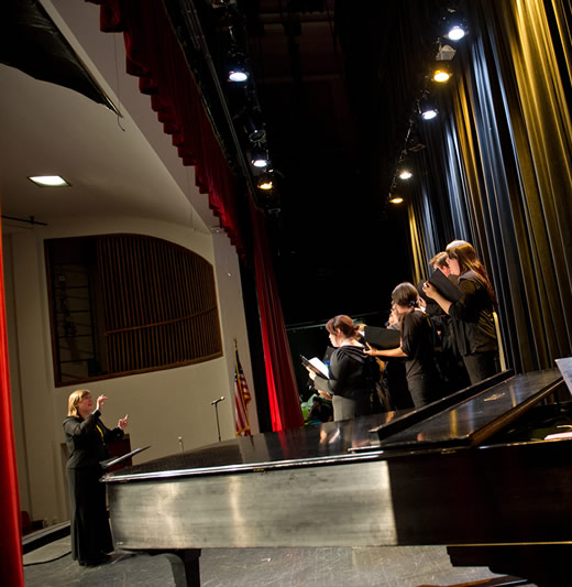 Music professor conducts students singing on stage