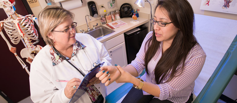 Female student in exam room with health services staff member