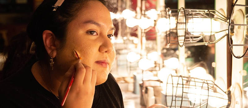 Female student applying stage makeup to her face