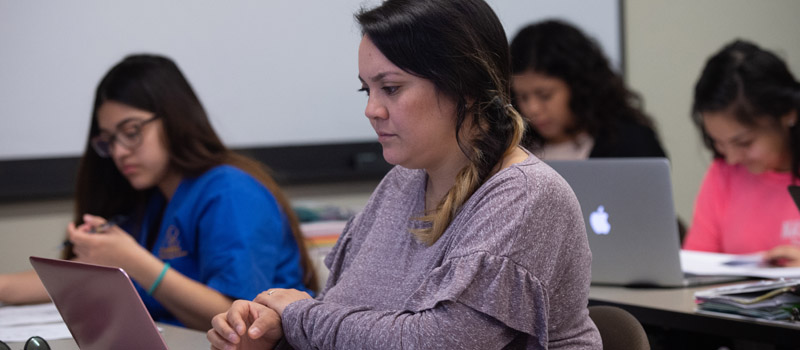 Female student working on laptop in classroom 