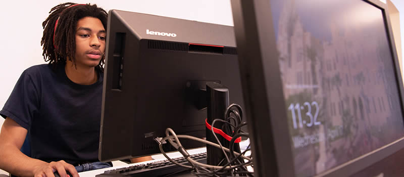 Male student sits at computer