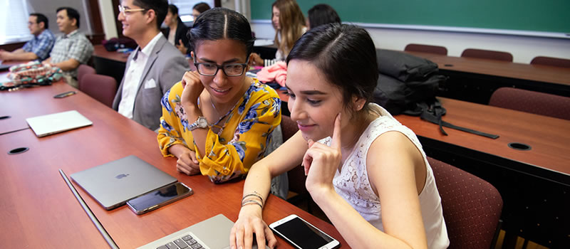 Two female students looking at laptop in class