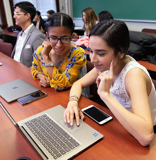 Two female students looking at laptop in class