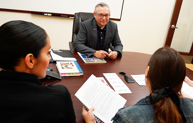 male professor speak with two female students