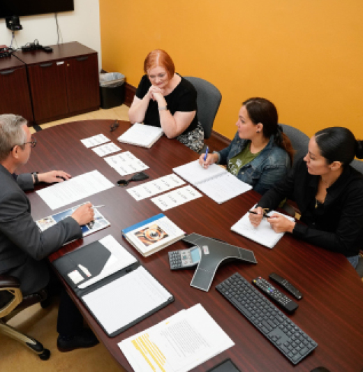 Professor and students sitting at conference table talking