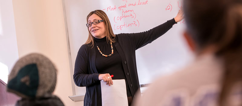 Female professor member pointing to information on whiteboard