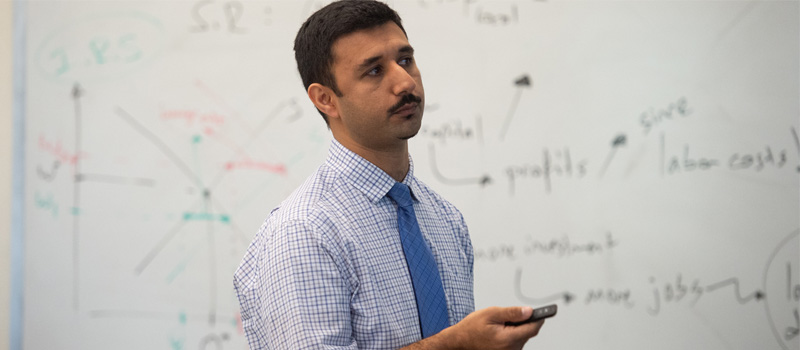 Professor stands in front of whiteboard