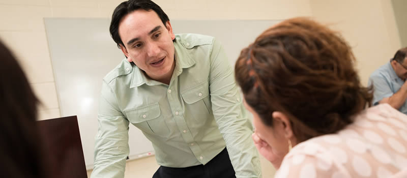 Male professor talks to female student in classroom