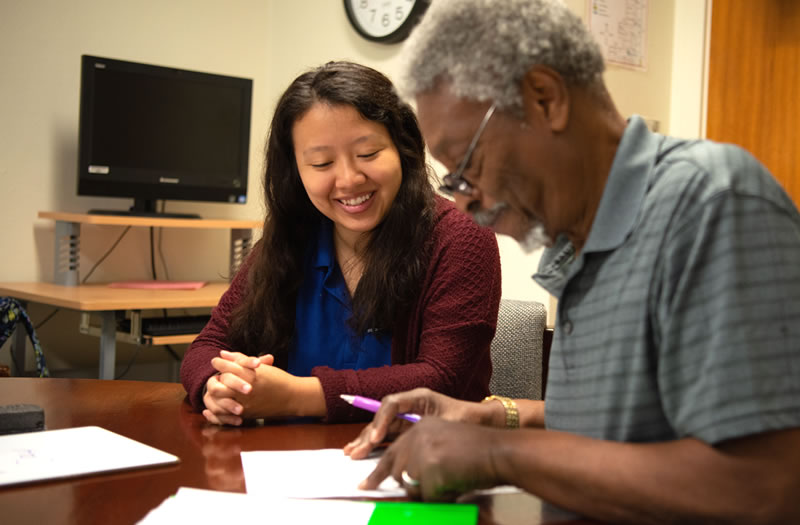 Female student helping older male with paperwork